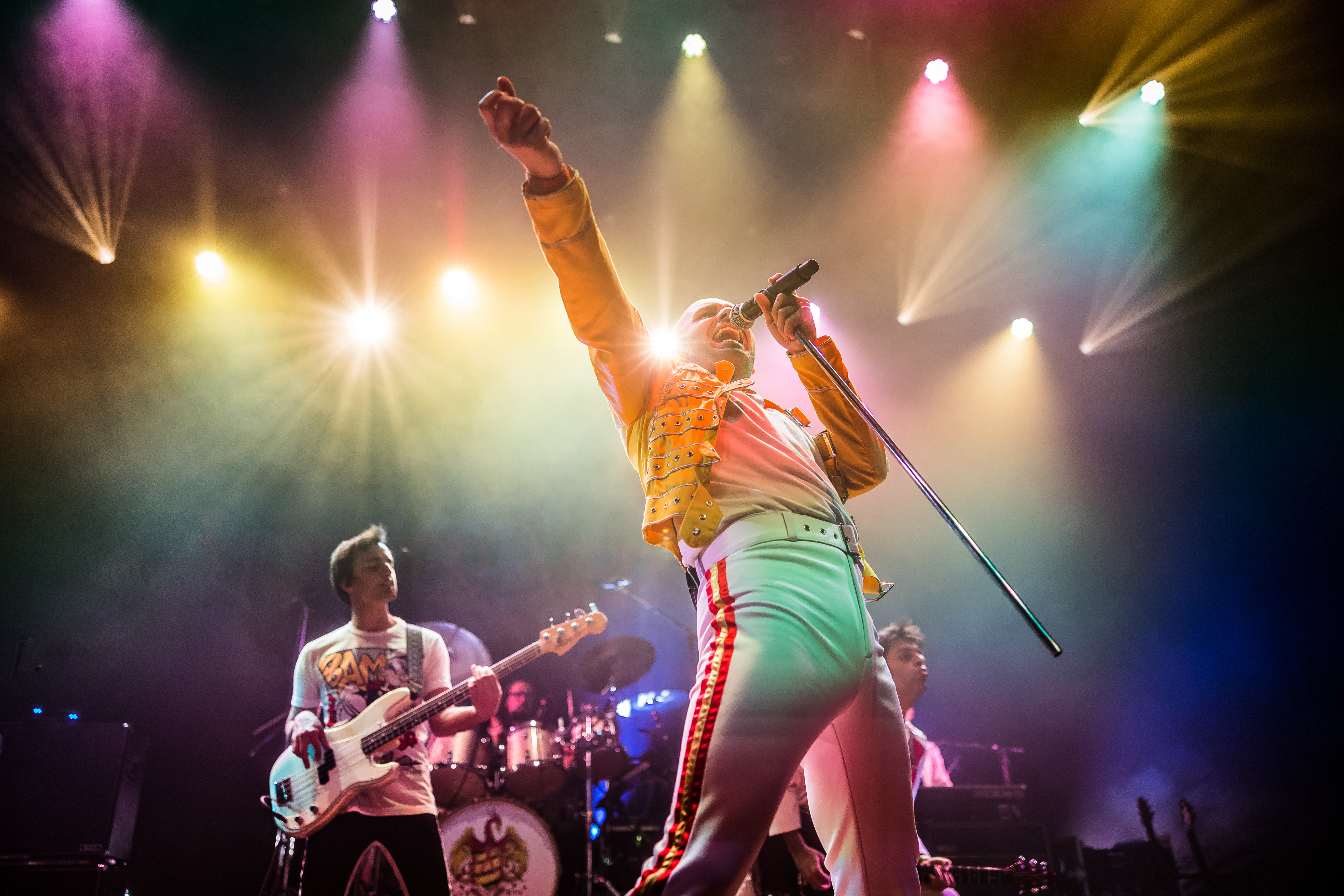 De leadzanger van Mother Mercury staat op de voorgrond, met de andere bandleden op de achtergrond.
